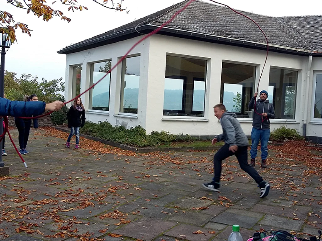 Jugendliche springen über ein gespanntes Seil.